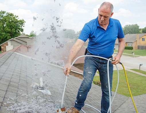a man above the roof cleaning a vent